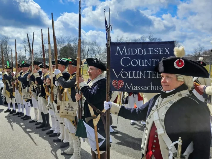 Men dressed in colonial outfits with muskets ready for parade