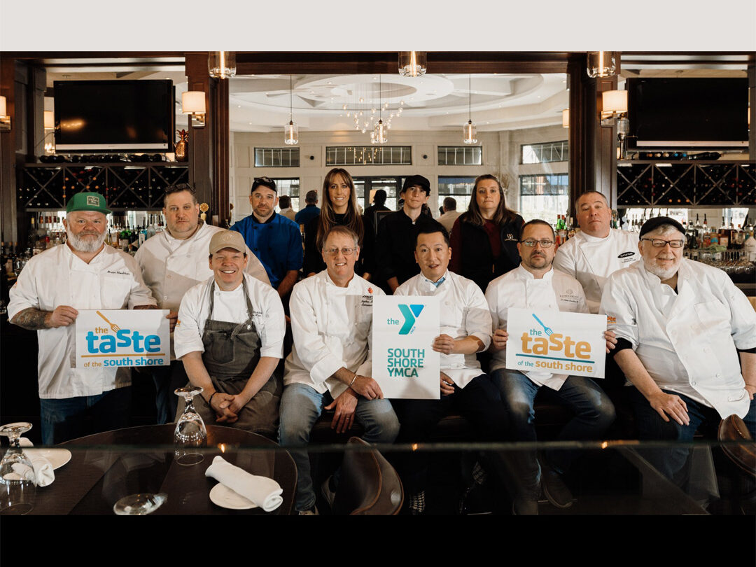 Group of Chefs gathered at a bar holding Taste of South Shore signs