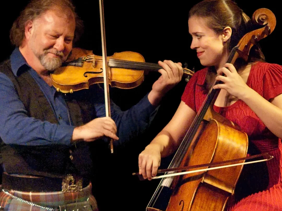 Cellist and Violinist smiling and playing their instruments