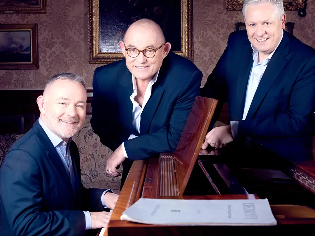 Ronan Tynan, Declan Kelly, Anthony Kearns gathered around a piano