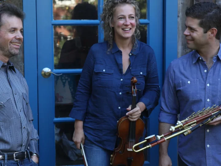 Band members all wearing blue and holding their instruments outside a blue and glass door