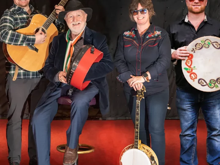 Derek Warfield and the Young Wolftones siting on a red couch holding their instruments